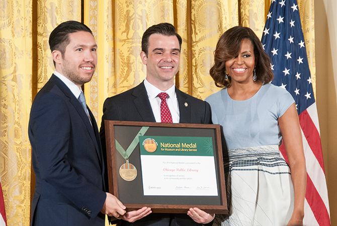 Brian Bannon holds National Medal. Michelle Obama stands to his right.